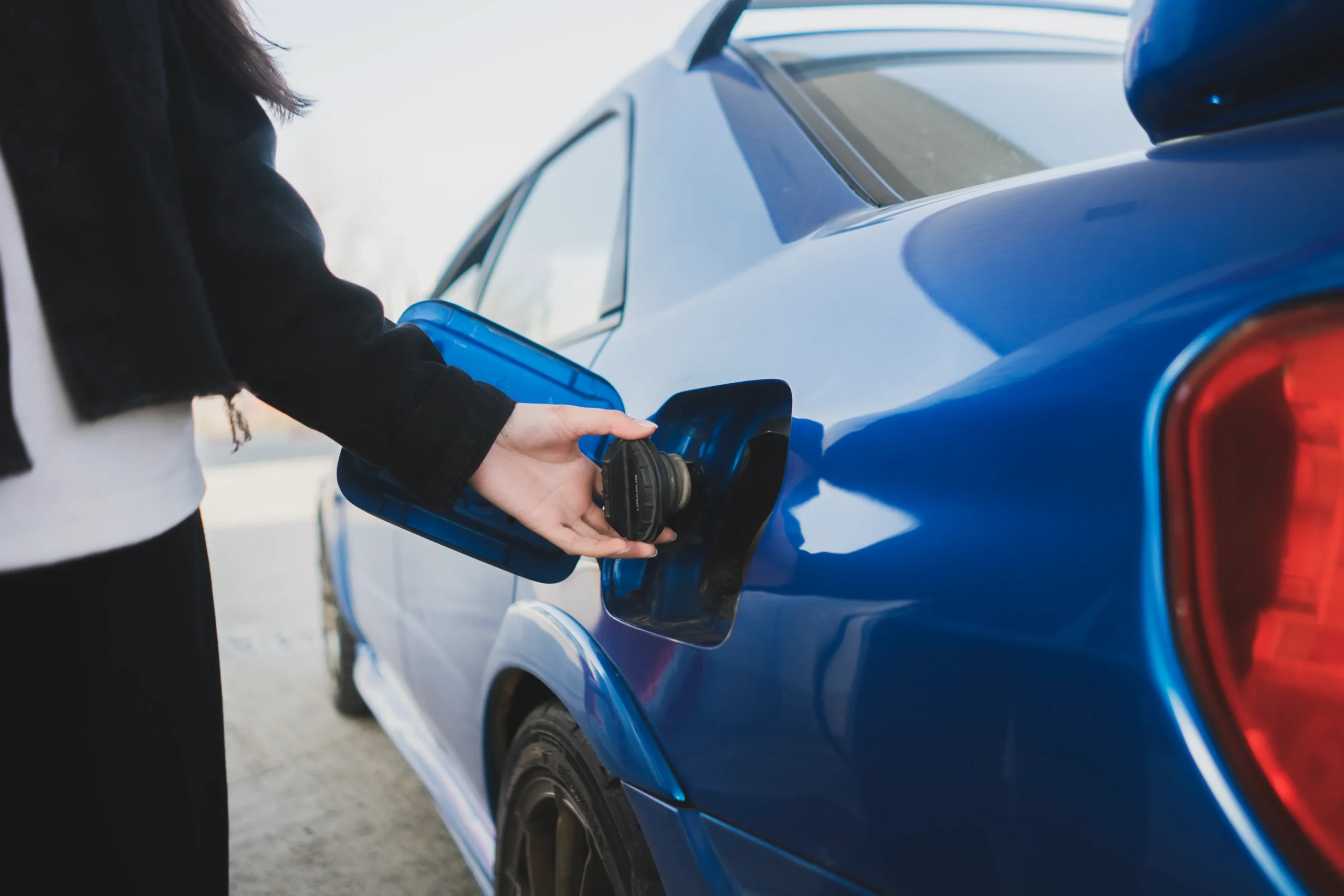 Opening Diesel Fuel Cap on Car Person opening fuel cap on a blue diesel vehicle at a fuel station.