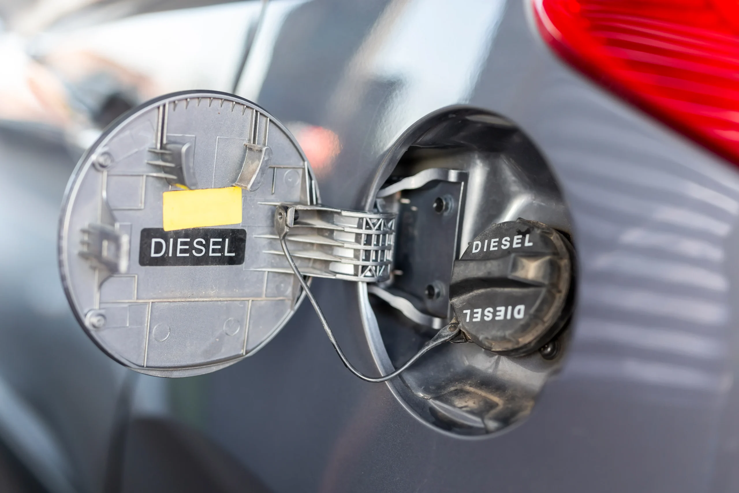 Close-up of a diesel fuel cap and filler flap on a silver vehicle.
